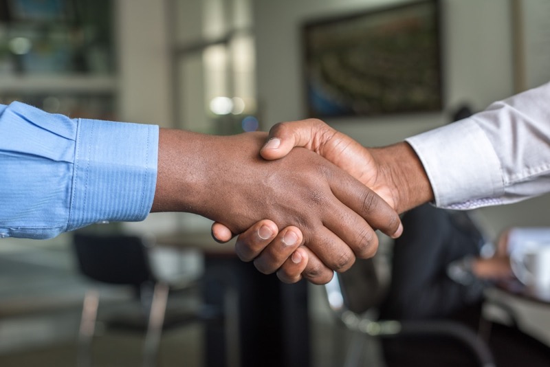 Two business owners shaking hands after agreeing on a sale
